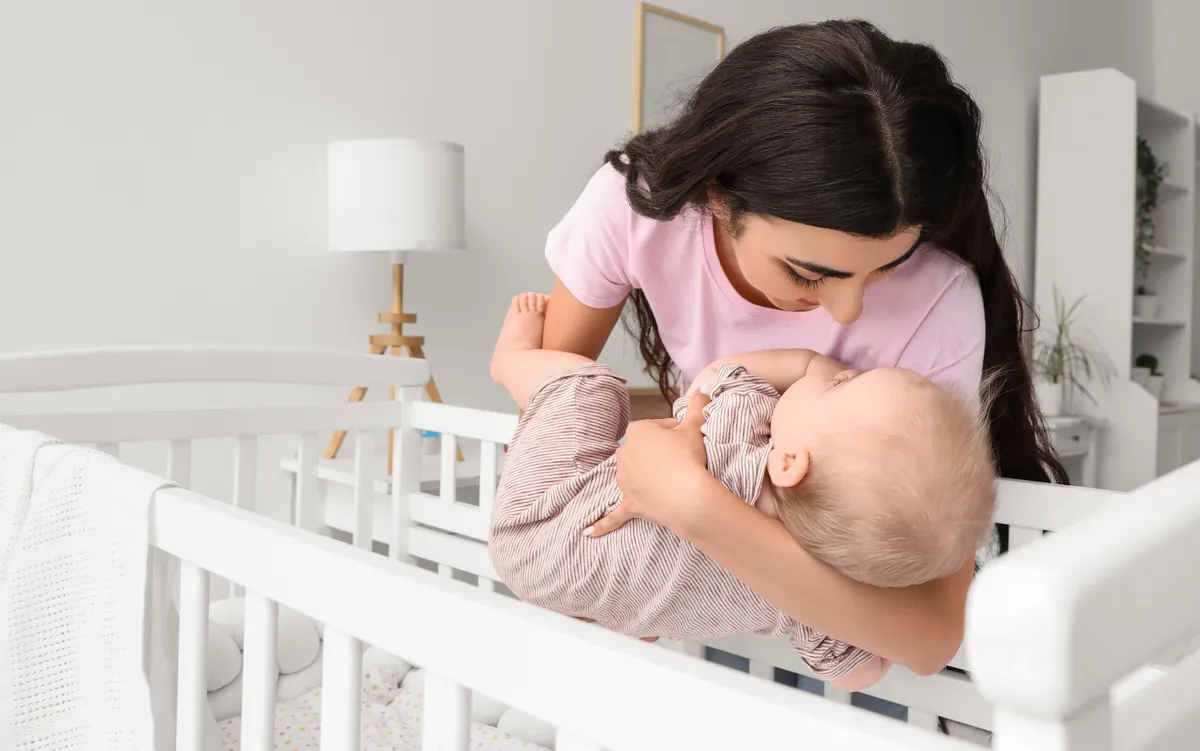 mamá acostando a su bebé en la cuna
